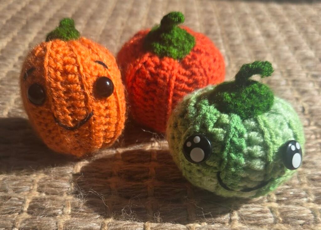 3 crochet pumpkins of different sizes and colours with different faces