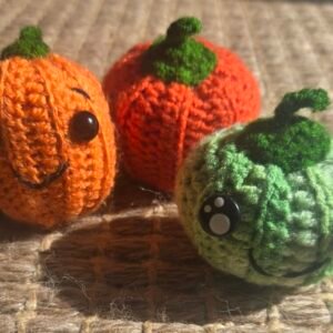 3 crochet pumpkins of different sizes and colours with different faces