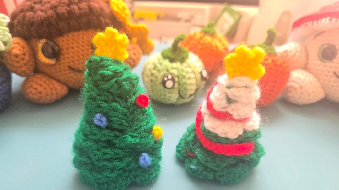 2 cute crochet christmas trees, one with baubles and one snow topped with added tinsel